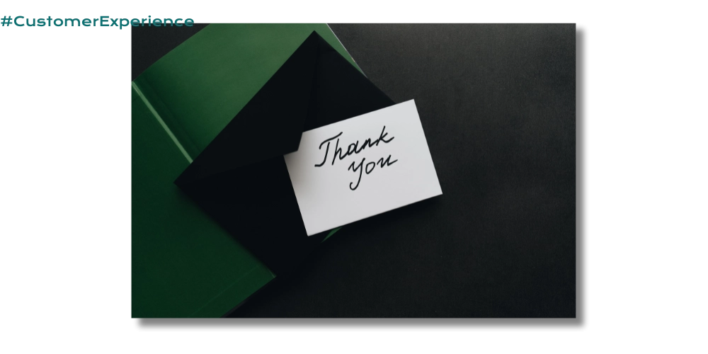 a flat lay photo of a white notecard that says "Thank You" on top of a black envelope which is on top of a green book on a dark black background which represents a high-end, hand crafted customer experience that delights clients and customers alike.